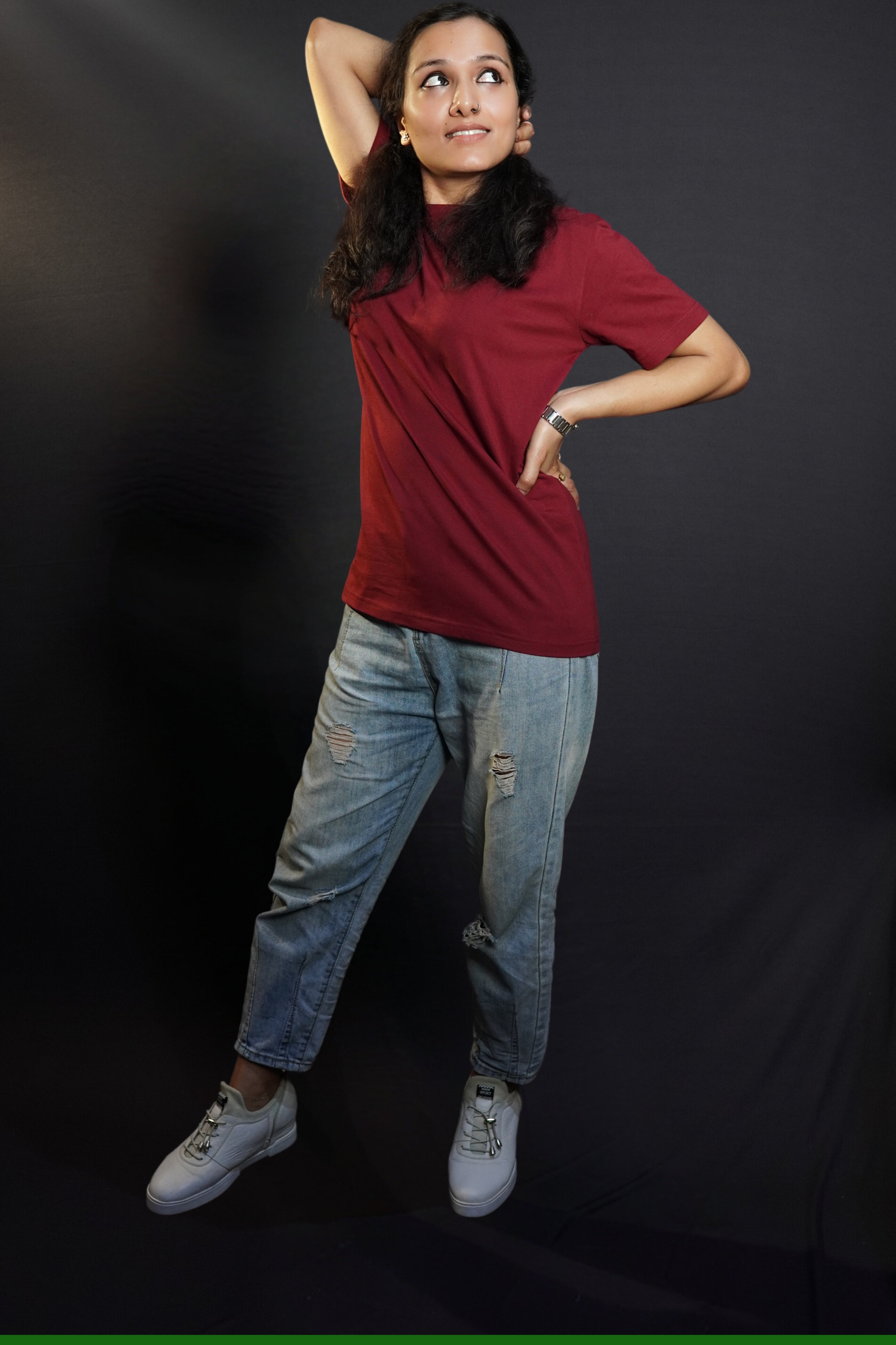 A woman posing with her hand up and behind her head and another on her waist, wearing a long length short sleeved moisture wicking rich maroon t-shirt, showcasing a loose flowing fit-Muselot