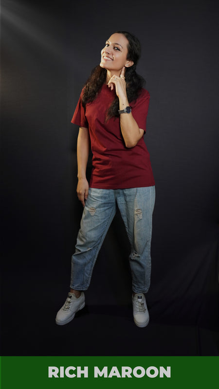 A woman wearing a girl's round neck stretchable rich maroon t-shirt, posing with her finger under her ear and other hanging on her side, showcasing a cool cozy look-Muselot