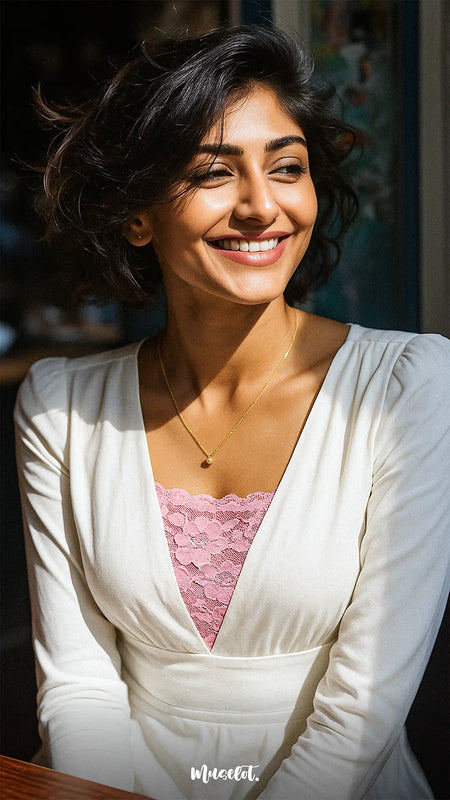 Model smiling in a white dress while wearing Lacy Light Pink Mockers, showcasing the delicate lace detail and soft, feminine touch it adds to deep-neck styles – Muselot.
