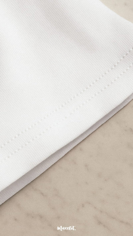 Close-up shot of an unisex oversized white t-shirt, showcasing the intricate fabric stitching,  and highlighting its premium texture and rich craftsmanship— Muselot.