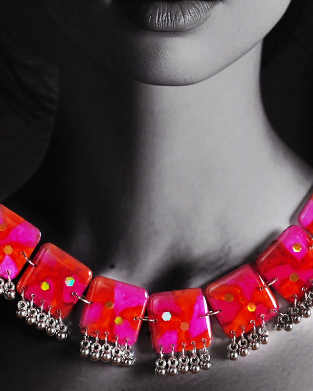 Close-up shot of a model wearing the Aynoor pink floral necklace from the jewelry set, featuring delicate pink floral motifs and intricate craftsmanship that add a refined and feminine touch to the look — Muselot.
