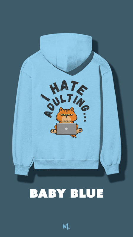 Baby blue hoodie featuring a cute grumpy cat sitting with a laptop and the text “I Hate Adulting,” showcased on a deep teal background – Muselot.