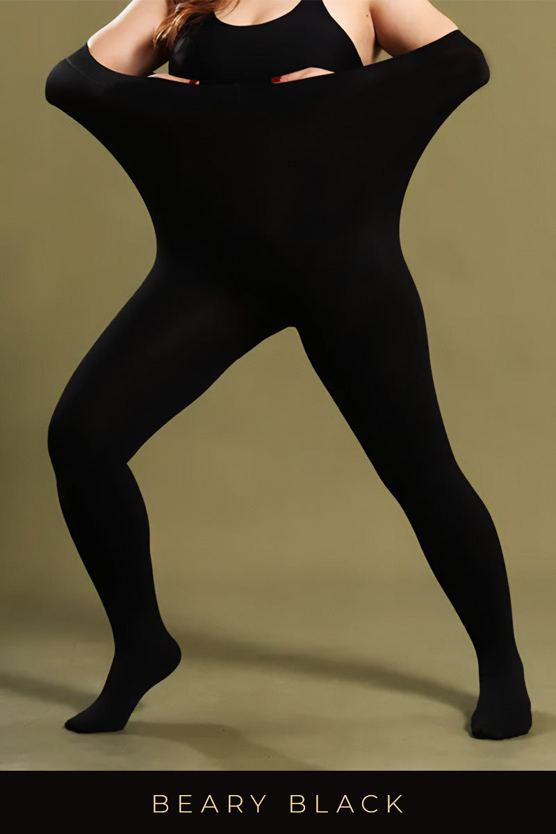 A woman in black stockings stretching the waistband to show elasticity, wearing a black top against an olive background - Muselot