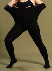 A woman in black stockings stretching the waistband to show elasticity, wearing a black top against an olive background - Muselot