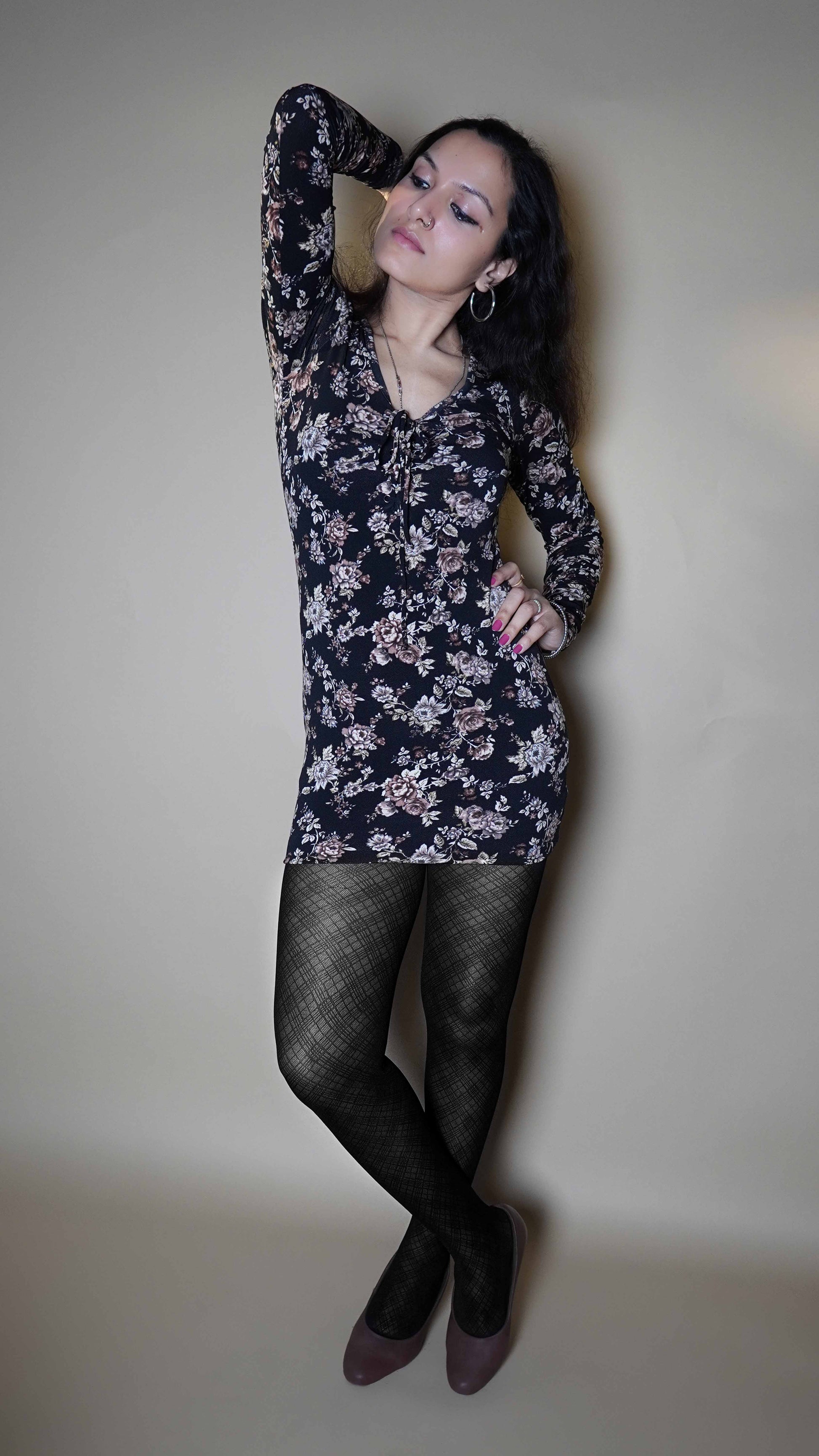 A model wearing black colored sheer pantyhose, posing with her hand up behind her head and other on her waist as she stands slightly sideways, showcasing the confidence that her tights bring-Muselot