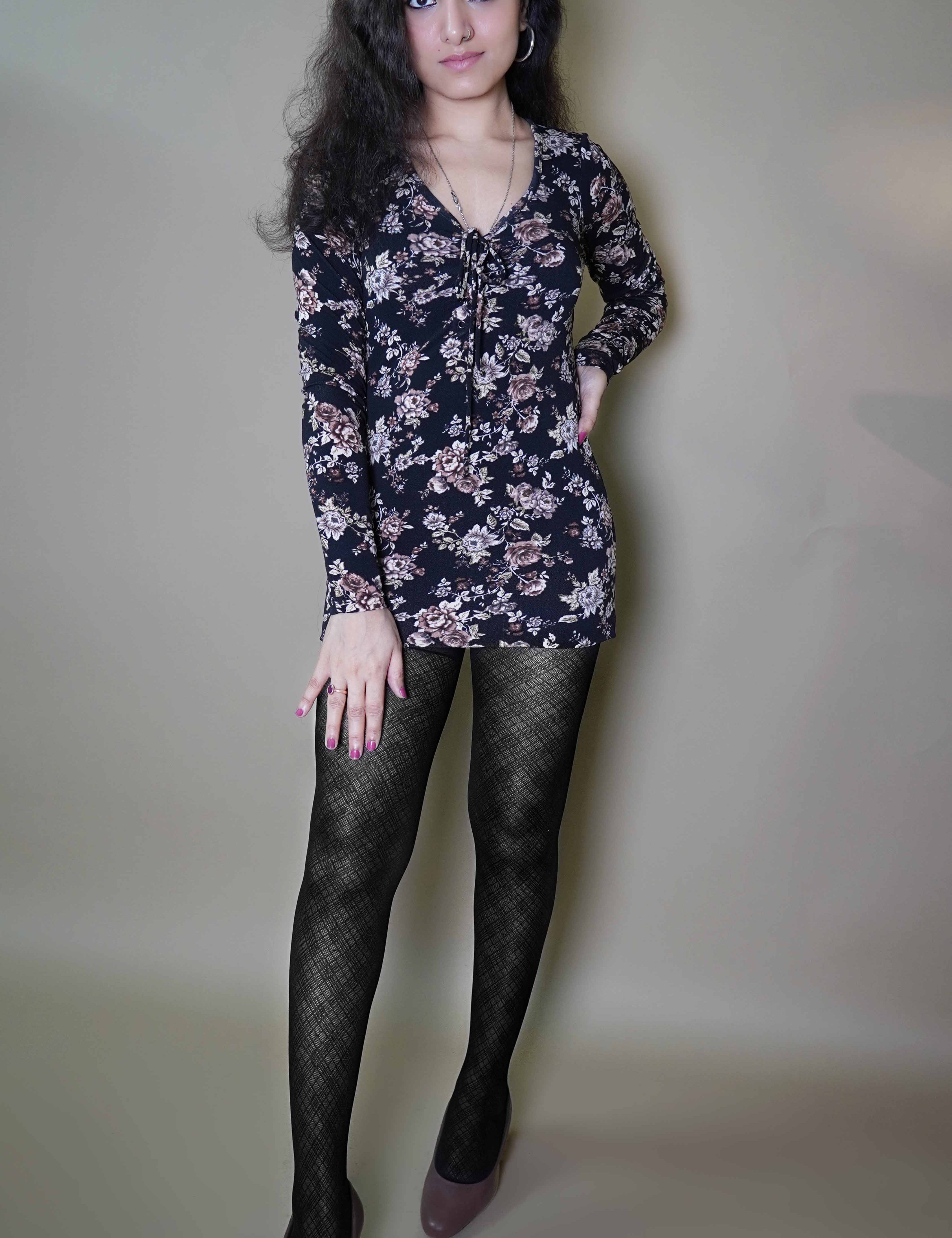 A woman wearing black lattice patterned sheer stockings, posing with her hand on her thigh and other on her waist, highlighting the durable smooth material-Muselot