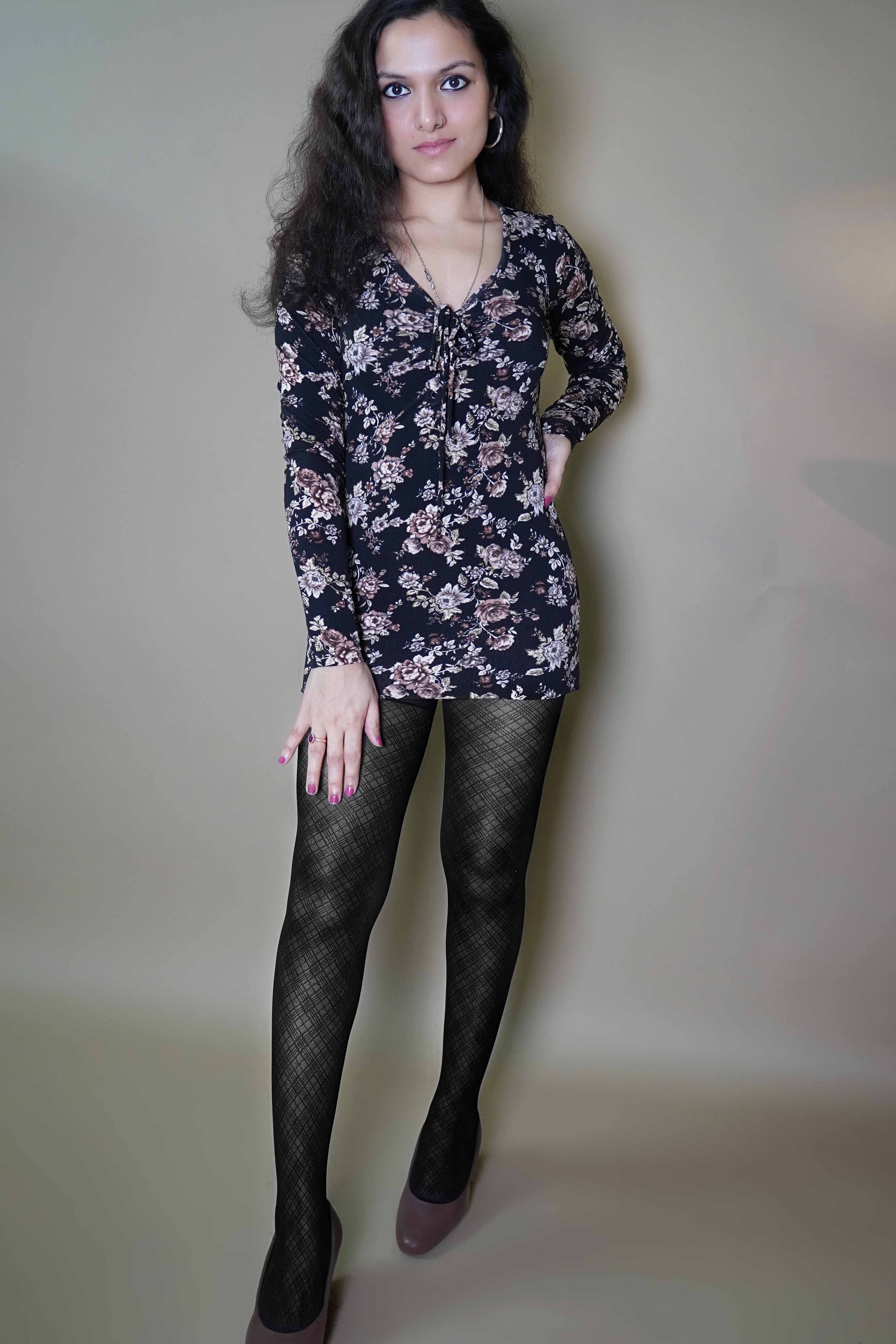 A woman wearing black lattice patterned sheer stockings, posing with her hand on her thigh and other on her waist, highlighting the durable smooth material-Muselot