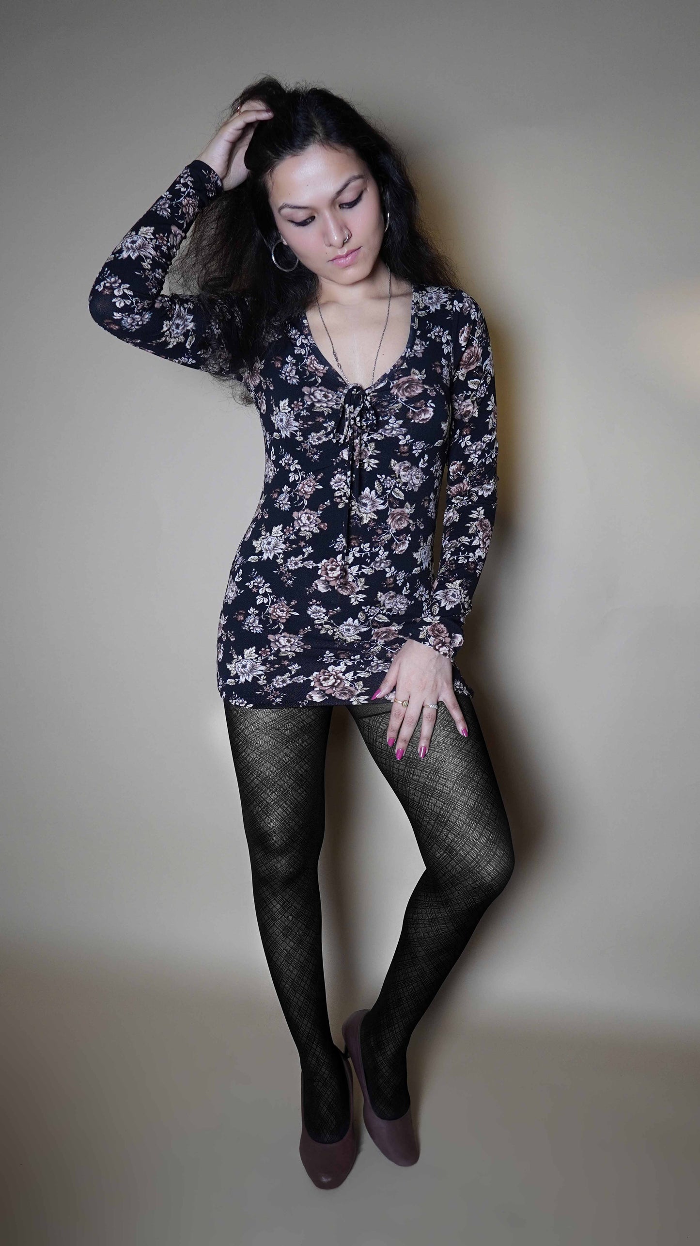 A woman wearing black girl's patterned sheer stockings, posing with her hand in her hair and other on her thigh, showcasing the perfect modish tights-Muselot