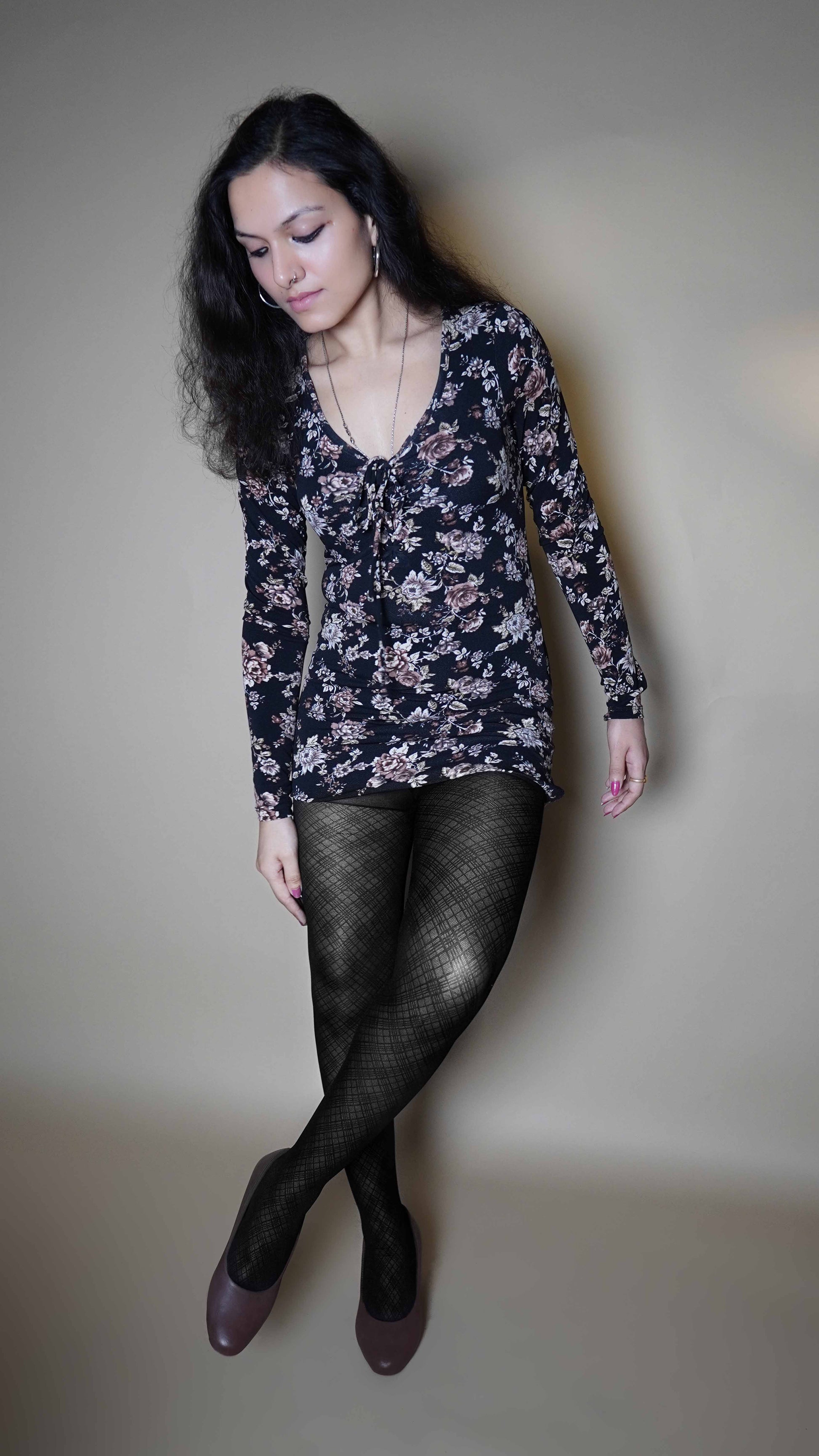 A woman wearing stretchable patterned sheer tights for women, posing with her legs crossed as she slightly bend forward, highlighting the classy pretty look-Muselot