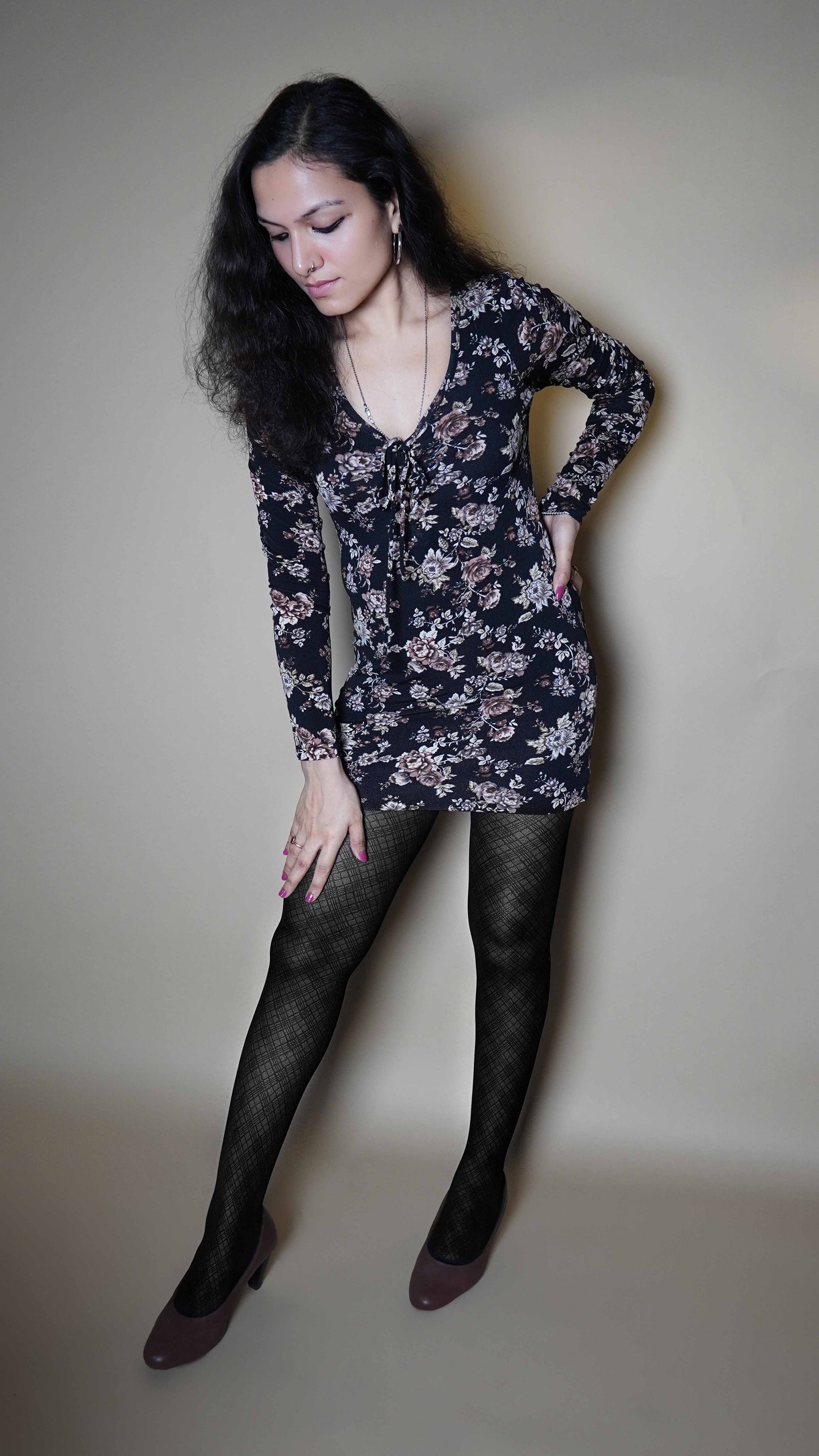 A woman wearing black moisture wicking sheer tights, posing with her hand on her waist and other on her thigh as she bends slightly forward, showcasing the perfect pattern of the stockings-Muselot