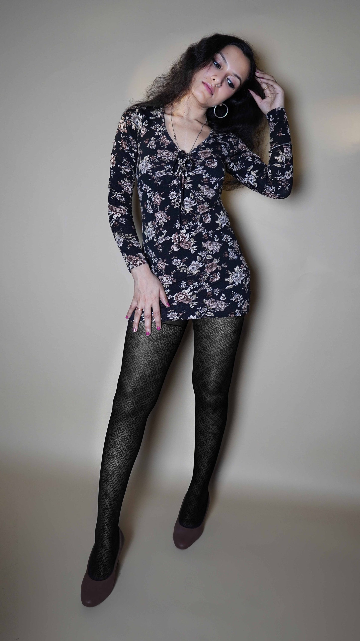 A woman wearing sheer patterned black comfortable pantyhose, posing with her leg stretched forward to show the perfect patterns of her stockings highlighting its durability and comfort-Muselot