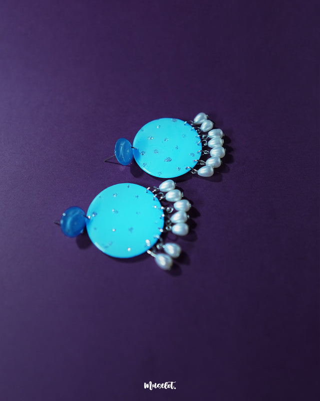Blue pearl earrings with small and large round turquoise blue discs embellished with fine silver glitter accents, finished with dangling white pearl-like beads, elegantly presented to highlight their festive and graceful design – Muselot.