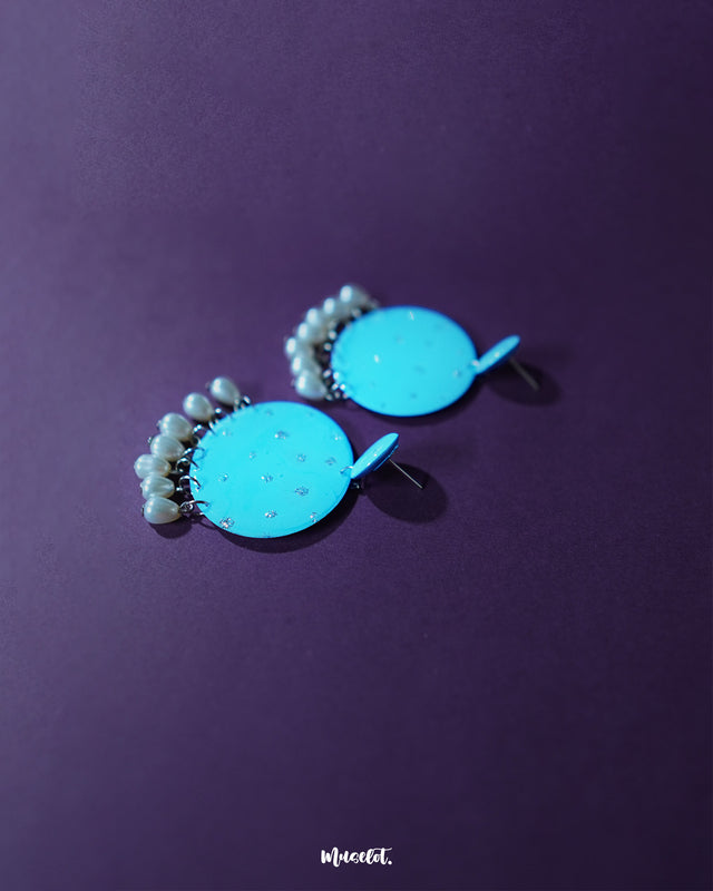 Blue pearl earrings with layered small and large turquoise blue discs adorned with delicate silver glitter accents, finished with dangling white pearl-like beads, beautifully presented to capture their bright and elegant appeal – Muselot.