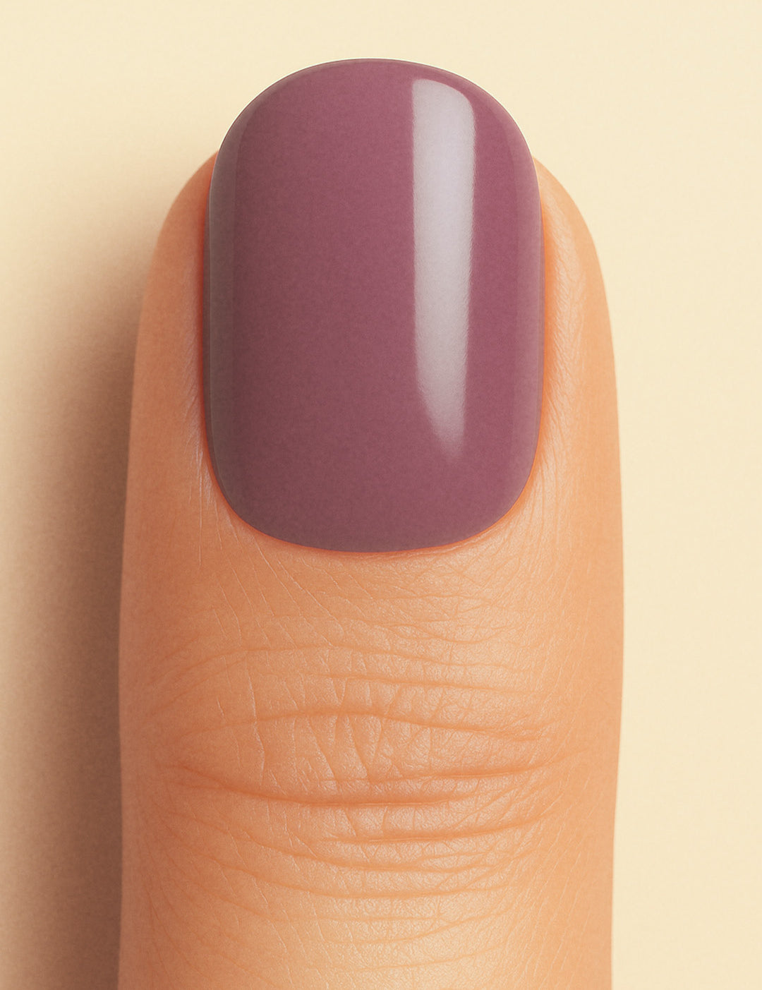 A close-up shot of a model’s thumb wearing Blushed Mauve nail stickies, showcasing the soft mauve shade with a smooth glossy solid finish, highlighting the elegance of minimal nail art in a refined and classy look – Muselot.