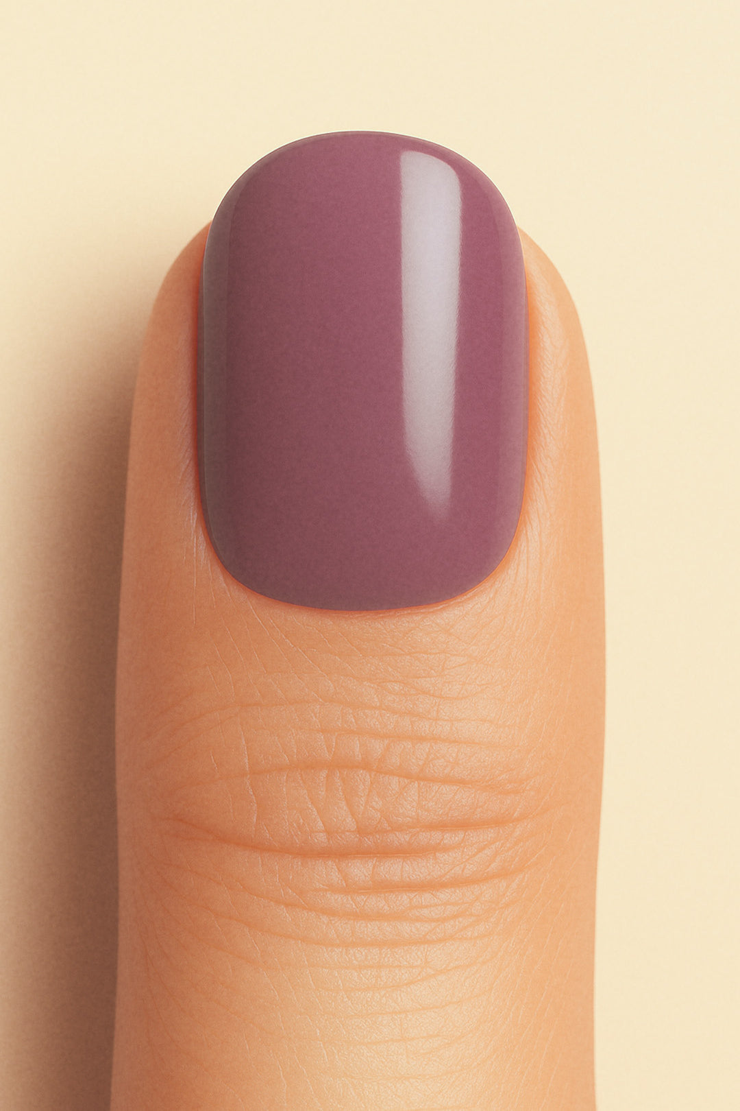 A close-up shot of a model’s thumb wearing Blushed Mauve nail stickies, showcasing the soft mauve shade with a smooth glossy solid finish, highlighting the elegance of minimal nail art in a refined and classy look – Muselot.
