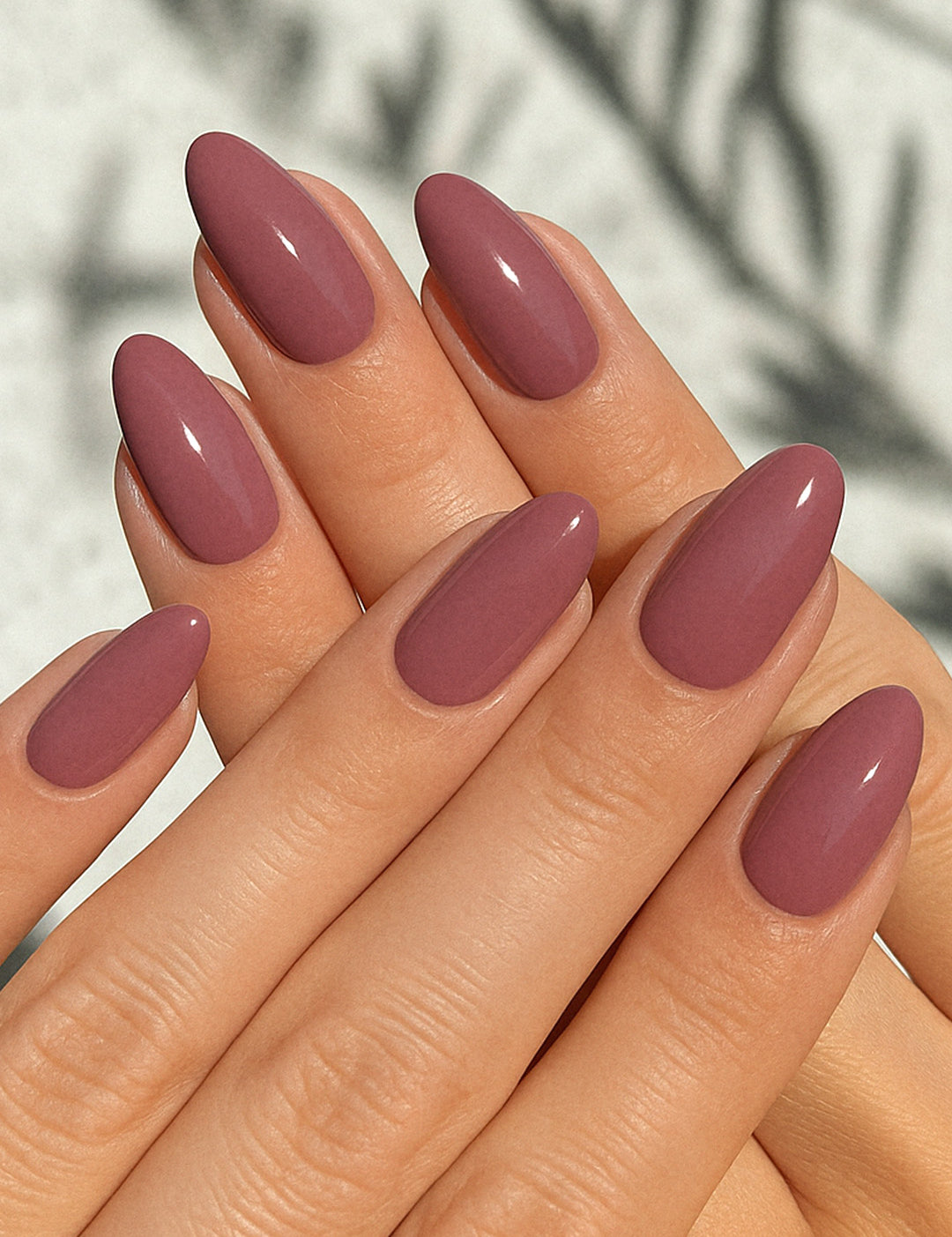 A shot of a model’s hand wearing Blushed Mauve nail stickies, showcasing the soft mauve shade in a glossy solid finish, highlighting the simplicity and shine of minimal nail art with a refined salon-style look – Muselot.