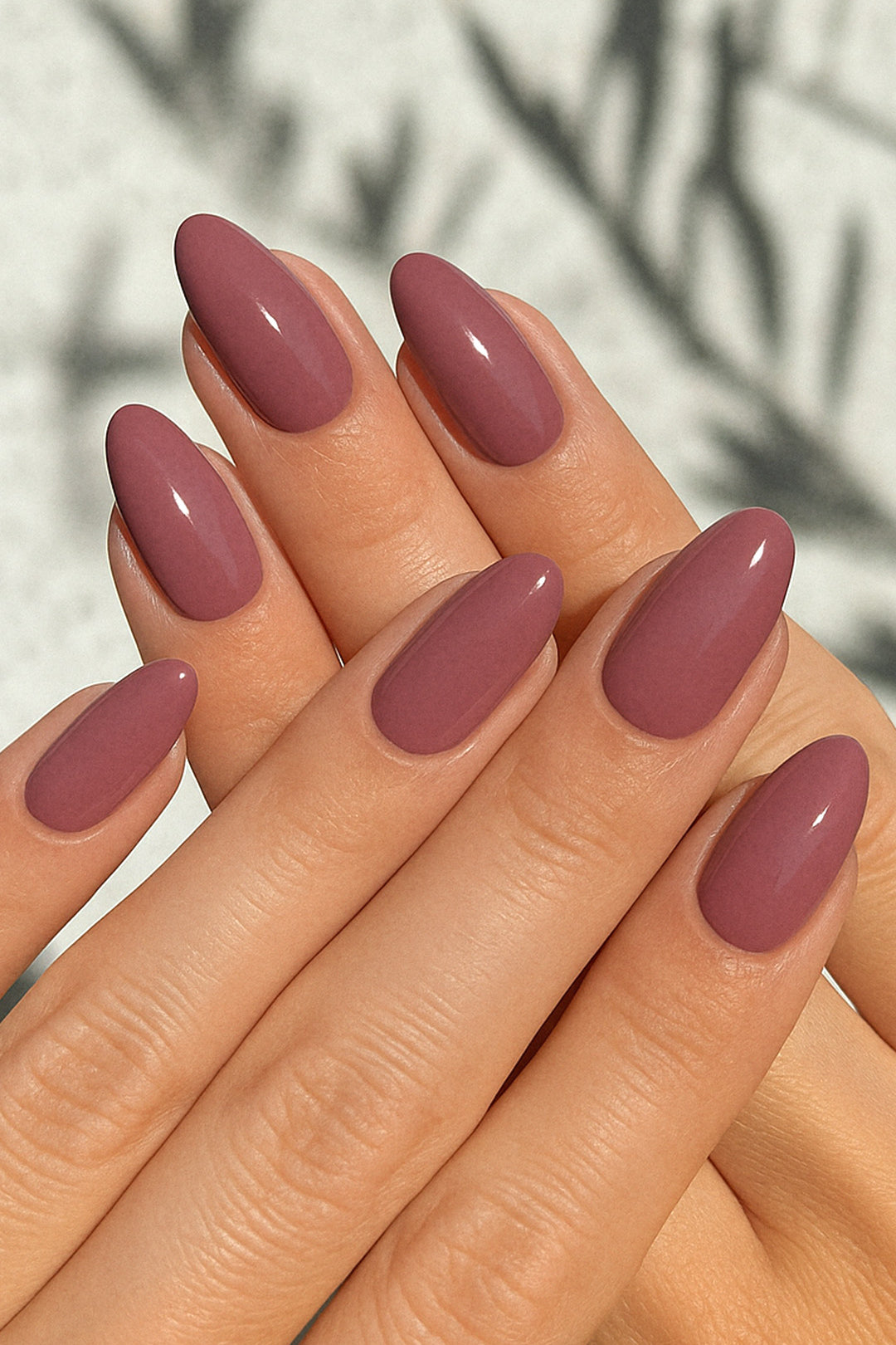 A shot of a model’s hand wearing Blushed Mauve nail stickies, showcasing the soft mauve shade in a glossy solid finish, highlighting the simplicity and shine of minimal nail art with a refined salon-style look – Muselot.