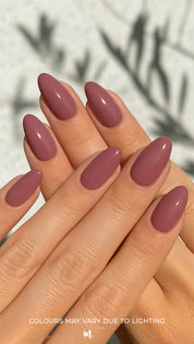 A shot of a model’s hand wearing Blushed Mauve nail stickies, showcasing the soft mauve shade in a glossy solid finish, highlighting the simplicity and shine of minimal nail art with a refined salon-style look – Muselot.