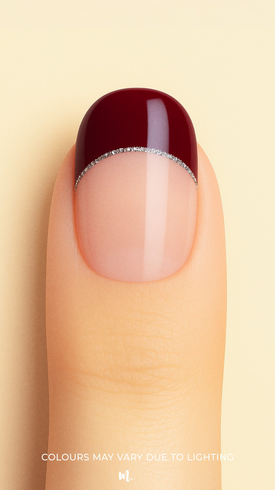 A close-up shot of a model’s finger wearing Cherry Moon French Tip nail stickies, showcasing a deep maroon glossy tip outlined with a fine silver glitter curve over a natural nude base, highlighting a bold and elegant French manicure style with a modern twist – Muselot.