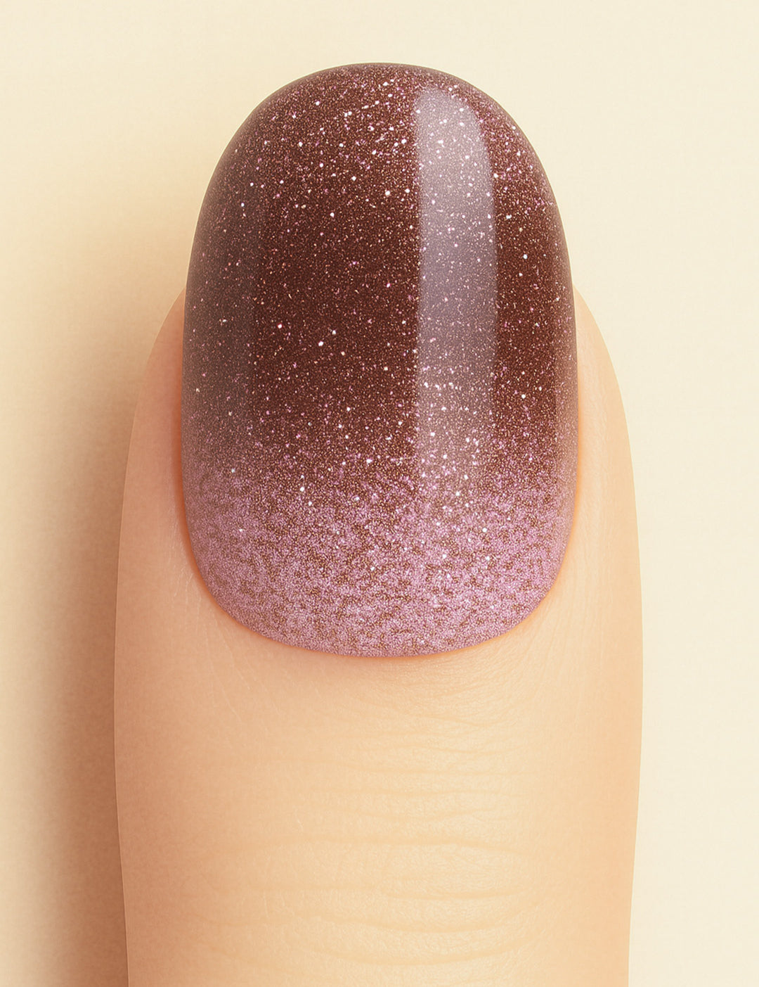A close-up shot of a model’s finger wearing Choco Plum Glitter Ombre nail stickies, showcasing the smooth gradient that shifts from soft plum to deep chocolate brown, highlighted with fine sparkling glitter for a rich ombre effect that adds depth, elegance, and a salon-style glossy finish – Muselot.
