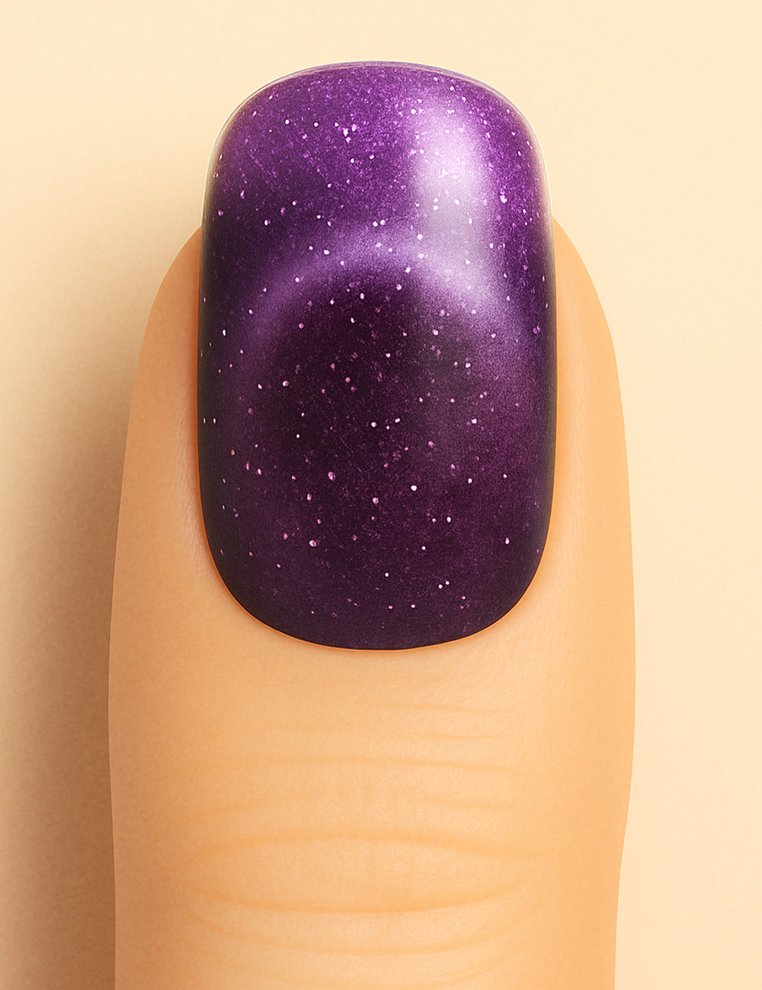 A close-up shot of a model’s finger wearing Cosmic Gaze Ombre nail stickies, showcasing a deep galaxy-purple shade that fades into subtle gradients, highlighted with tiny star-like specks for a celestial effect, emphasizing the bold and cosmic allure of ombre glitter nail art – Muselot.