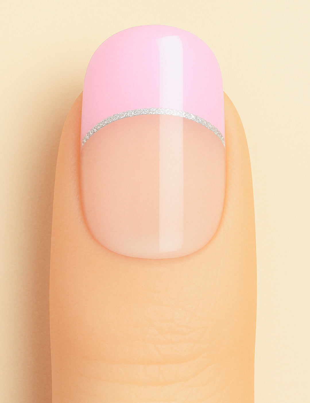 A close-up shot of a model’s finger featuring Crowned Petal French Tip nail stickies, designed with a glossy pastel pink tip accented by a sleek silver glitter line over a natural nude base, creating a chic and feminine French manicure look – Muselot.