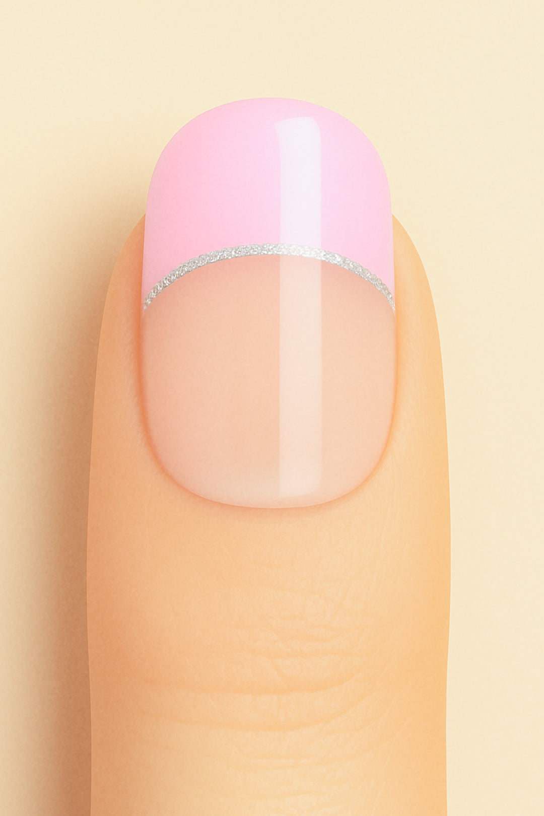A close-up shot of a model’s finger featuring Crowned Petal French Tip nail stickies, designed with a glossy pastel pink tip accented by a sleek silver glitter line over a natural nude base, creating a chic and feminine French manicure look – Muselot.