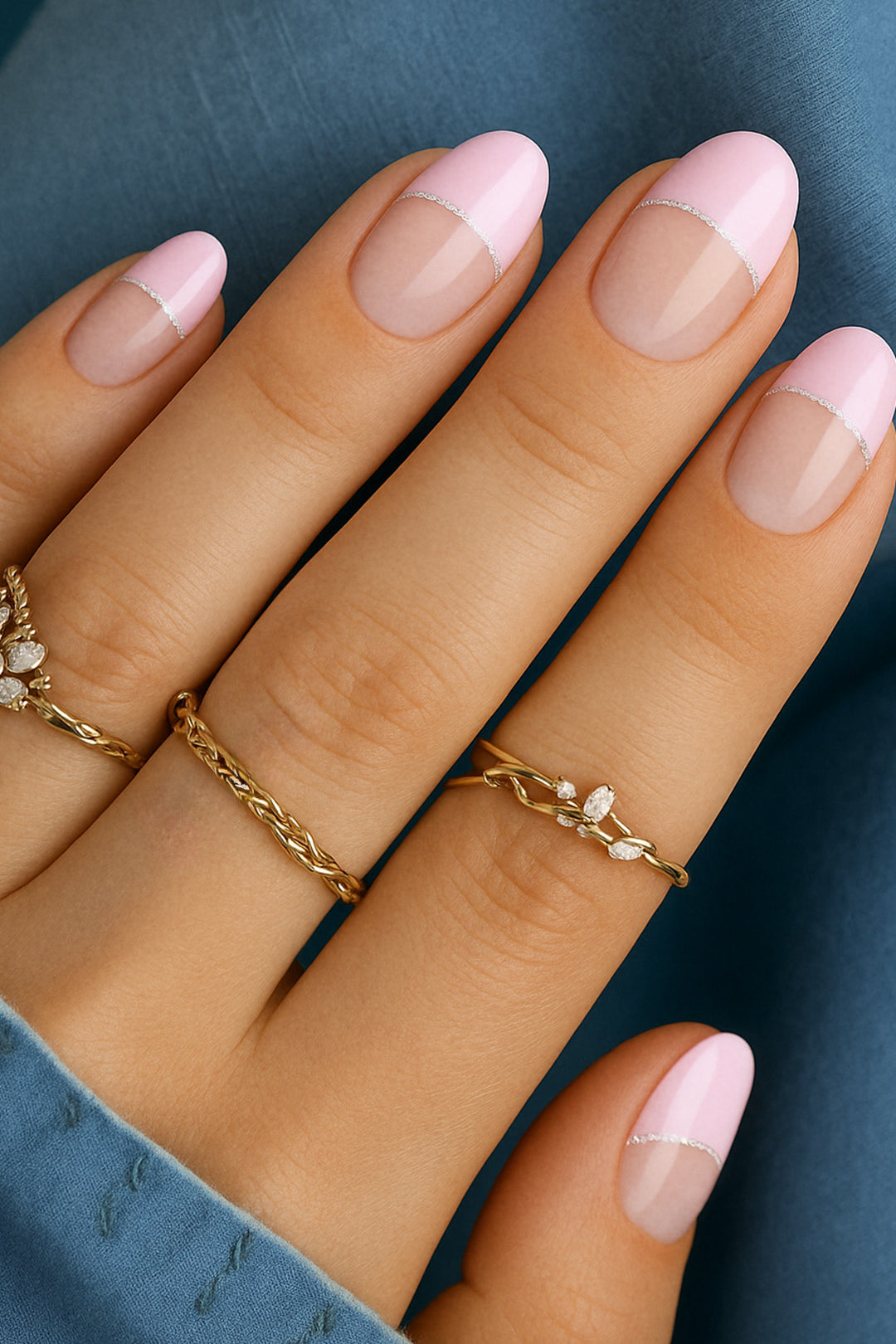 A close-up of a model’s hand featuring the Crowned Petal French Tip nail stickies, designed with a glossy baby pink tip outlined by a fine silver glitter curve over a natural nude base, creating a chic and playful French manicure look – Muselot.