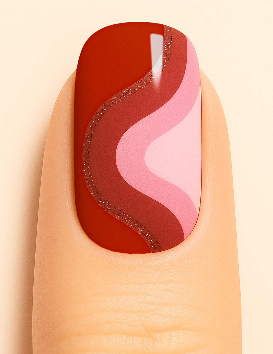 A close-up of a finger wearing Dried Rose Nail Stickies, featuring bold wavy patterns in deep red, dusty rose, and soft pink, outlined with a touch of glitter for added elegance. The design creates a retro-modern vibe, making the manicure stand out with its artistic curves and chic finish – Muselot.