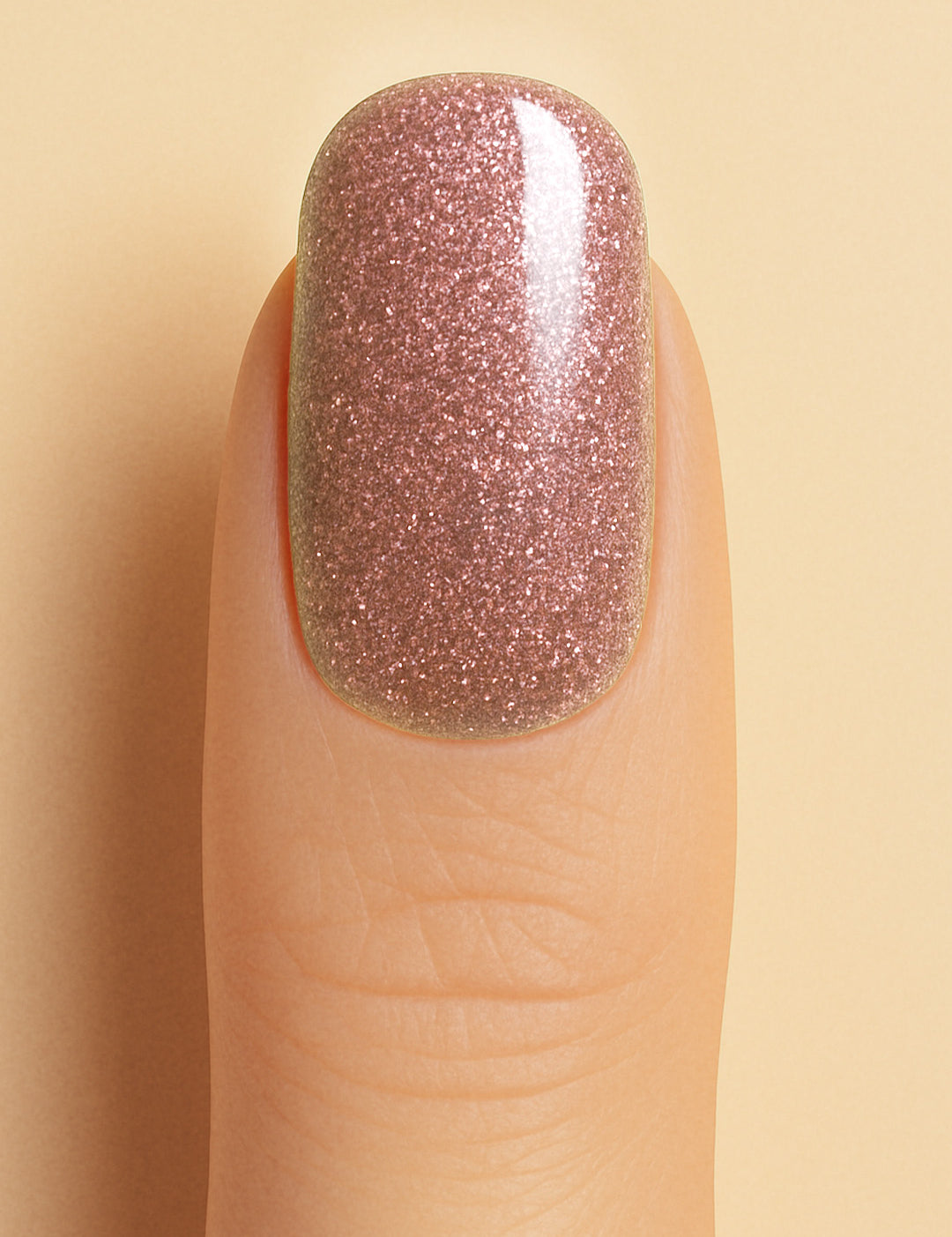 A close-up shot of a model’s finger wearing Dusty Rose Glitter nail stickies, showcasing the soft rose-pink shade filled with fine glitter sparkles, highlighting the elegance and charm of minimal nail art with a shimmering glossy finish – Muselot.