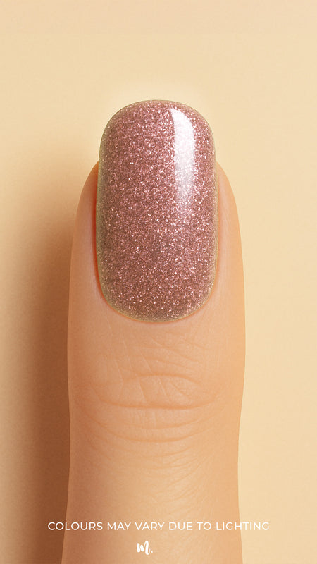 A close-up shot of a model’s finger wearing Dusty Rose Glitter nail stickies, showcasing the soft rose-pink shade filled with fine glitter sparkles, highlighting the elegance and charm of minimal nail art with a shimmering glossy finish – Muselot.