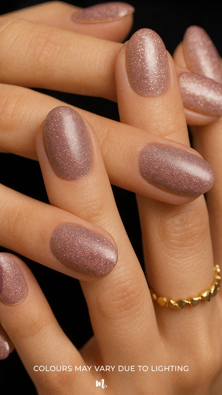 A shot of model hands wearing Dusty Rose Glitter nail stickies, showcasing the soft rose-pink shade filled with fine glitter sparkles, highlighting the shimmer and elegance of minimal nail art in a glossy salon-style finish – Muselot.
