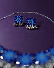Falakzaar blue floral earring set placed on a light backdrop, highlighting intricate floral detailing and showcasing the harmonious blend of blue and soft pastel shades — Muselot.