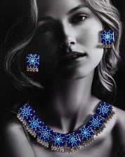 A woman wears the Falakzaar blue necklace set, showcasing the handcrafted mandala tile design and silver bead detailing that highlight the bold elegance of this statement accessory — Muselot.