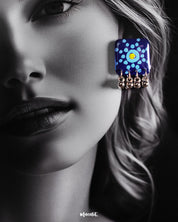 A model flaunts the Falakzaar blue earrings from the set, highlighting the vibrant hand-painted mandala motifs and silver bead drops that add a traditional yet trendy charm — Muselot.