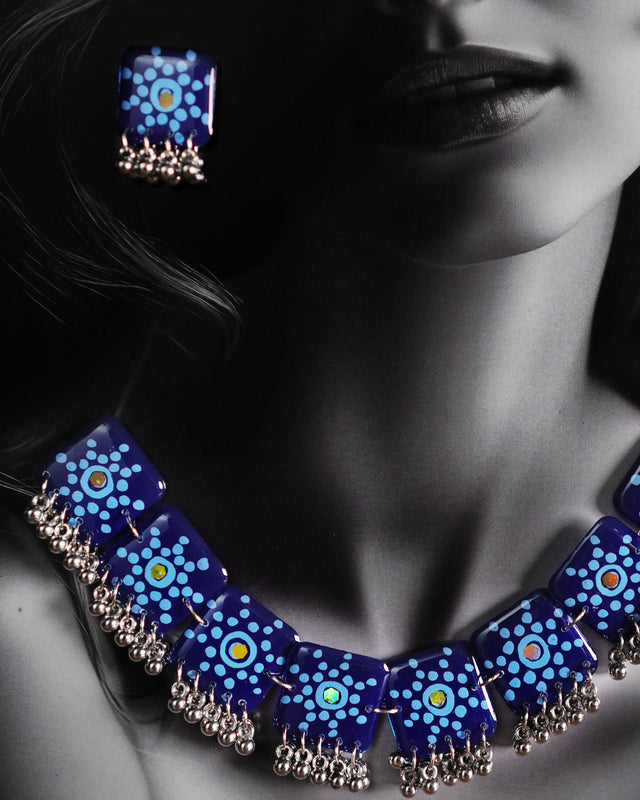 A model wears the Falakzaar blue necklace set, showcasing the handcrafted square tiles adorned with intricate blue mandala patterns and silver bead detailing, making it a statement piece for festive elegance — Muselot.