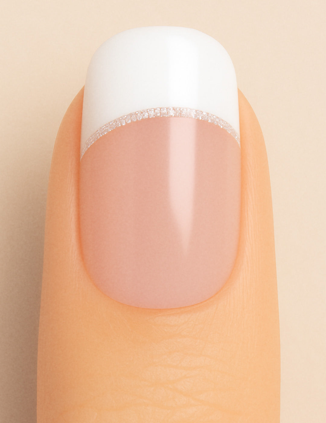 A close-up of a model’s finger featuring Frosted Charm French Tip Nail Stickies by Muselot, designed with a classic white French tip accented by a fine line of subtle glitter, giving a timeless and elegant manicure look with a glossy finish.