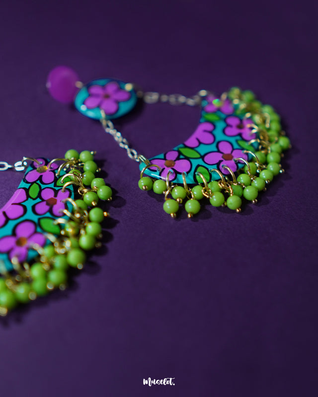 Gulbahaar chandbali earrings featuring a lively mix of purple and green floral motifs with yellow bead hangings, showcasing a vibrant boho charm against a purple backdrop — Muselot.