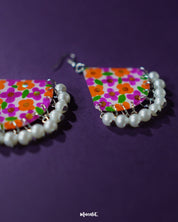 Front view of Guldaan floral earrings, showcasing bold multicolour hand-painted flowers and pearl drop accents on a clean backdrop – Muselot.