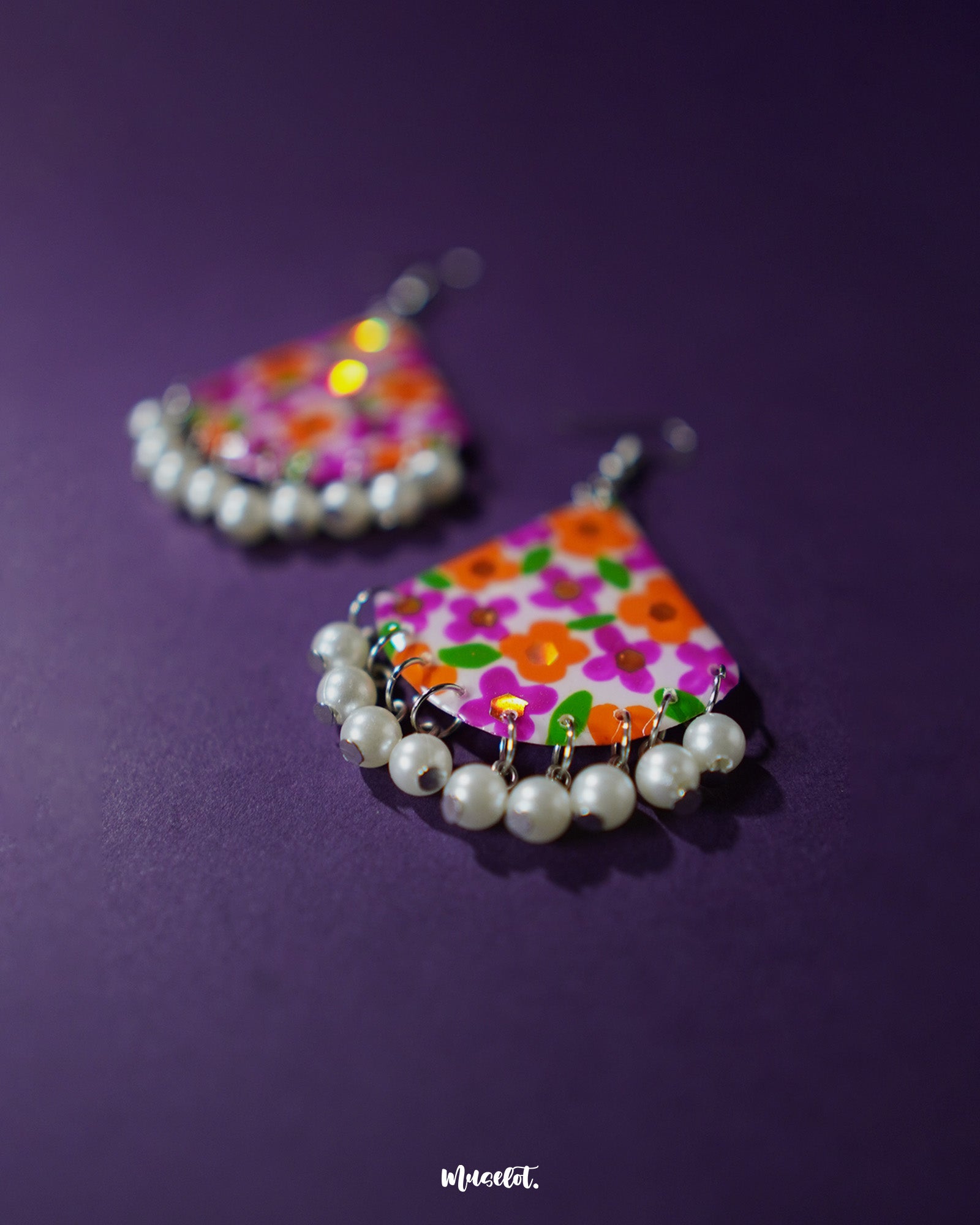 Close-up of Guldaan floral earrings, capturing the vibrant hand-painted flowers and glossy pearl drop detail against a simple backdrop – Muselot.
