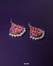 Pair of Guldaan floral earrings laid flat, showcasing multicolour hand-painted blooms and elegant pearl drops on a neutral background – Muselot.