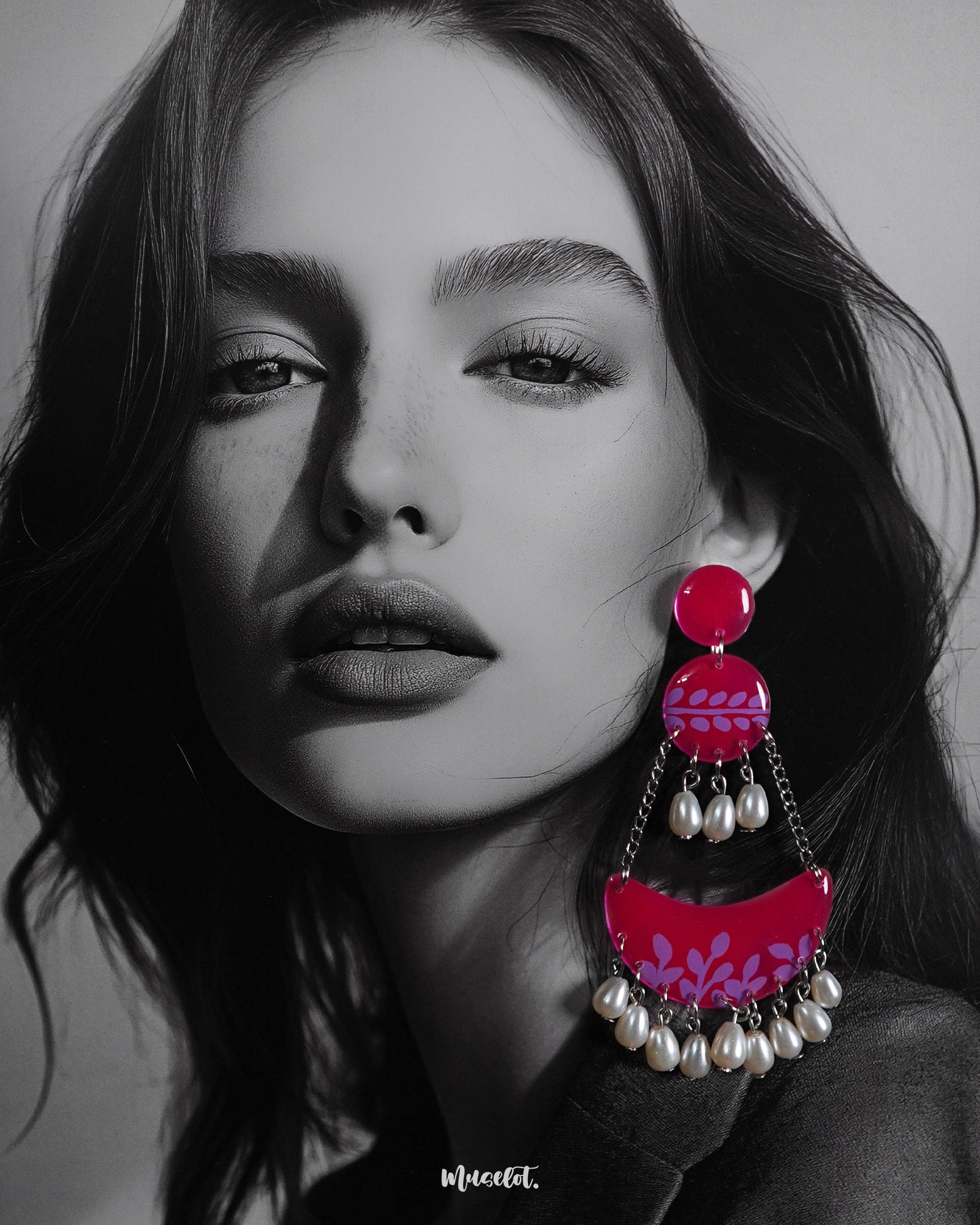 A woman wears the Gulfaam chandbali earrings, where the vibrant hot pink crescent design with lilac botanical motifs and dangling pearl drops adds a bold yet elegant touch to her look, perfectly capturing a playful, festive spirit — Muselot.
