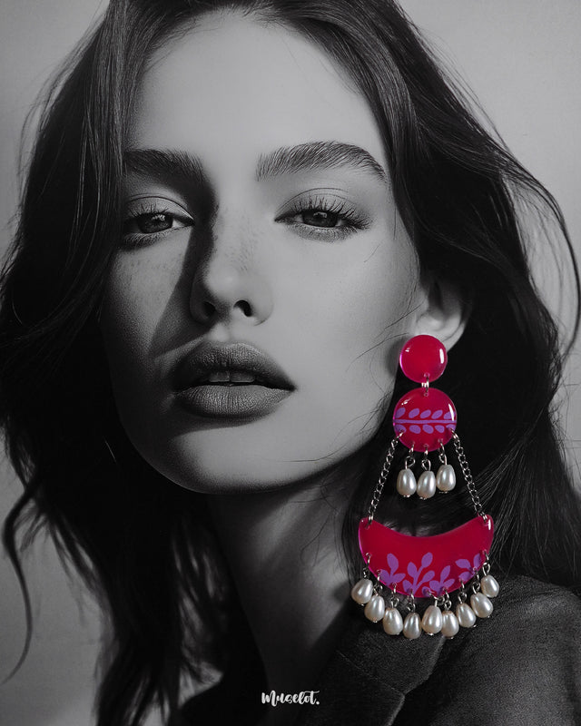 A woman wears the Gulfaam chandbali earrings, where the vibrant hot pink crescent design with lilac botanical motifs and dangling pearl drops adds a bold yet elegant touch to her look, perfectly capturing a playful, festive spirit — Muselot.
