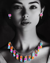 A model gracefully showcases the Gulraas handmade floral necklace set, where vibrant rectangular charms bloom in a rainbow of hand-painted florals—highlighting the whimsical spirit and statement appeal of this artisanal creation — Muselot.
