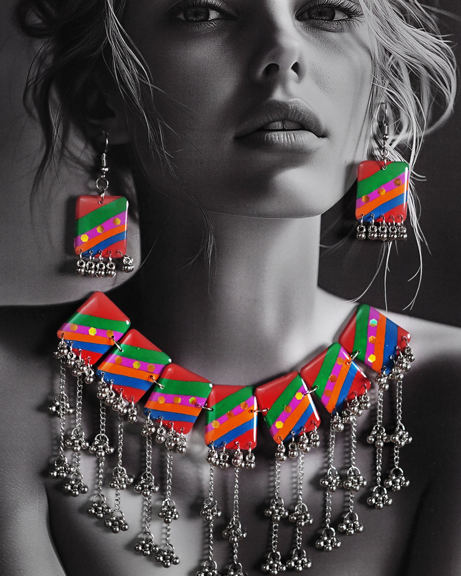 Model wearing the Gulrang multicolor resin jewelry set, featuring a statement silver chain necklace with bold red, green, blue, and purple striped rectangular charms and cascading silver bead tassels, paired with matching earrings, emphasizing its colorful and striking design – Muselot.