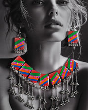 Model wearing the Gulrang multicolor resin jewelry set, featuring a statement silver chain necklace with bold red, green, blue, and purple striped rectangular charms and cascading silver bead tassels, paired with matching earrings, emphasizing its colorful and striking design – Muselot.
