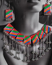 Close-up of model wearing the Gulrang multicolor resin jewelry set, highlighting the bold red, green, blue, and purple striped rectangular charms with dotted accents and cascading silver bead tassels on the necklace, paired with matching earrings, capturing the vibrant details and craftsmanship – Muselot.