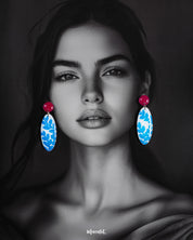 Model wearing the Gulsaba drop earrings, featuring glossy red circular studs with elongated oval drops in white adorned with hand-painted blue leafy patterns, elegantly highlighting their vibrant and contemporary style – Muselot.