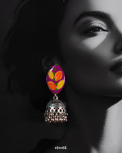 Close-up of model wearing the Gulzarish jhumkas, featuring marquise-shaped purple tops with orange and yellow leaf motifs accented by green dots, paired with ornate oxidized silver dome-shaped jhumka drops adorned with delicate hanging beads, capturing their intricate detailing and vibrant design – Muselot.