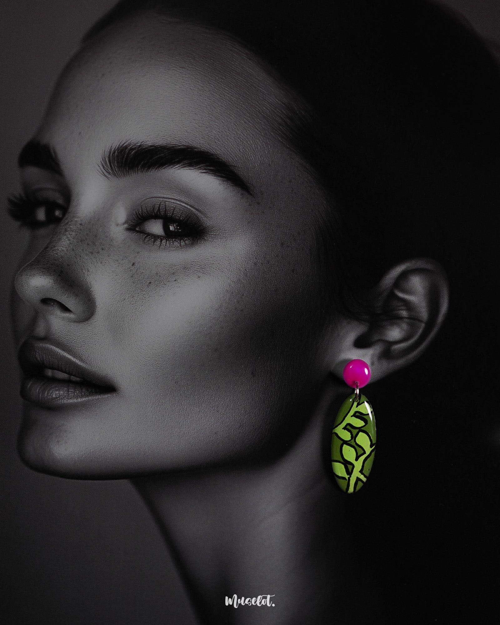 A woman wearing the Naghma handmade leaf drop earrings is seen posing gracefully, highlighting and showcasing the vivid green leaf design and striking magenta studs that bring a bold, artistic flair to her look — Muselot.